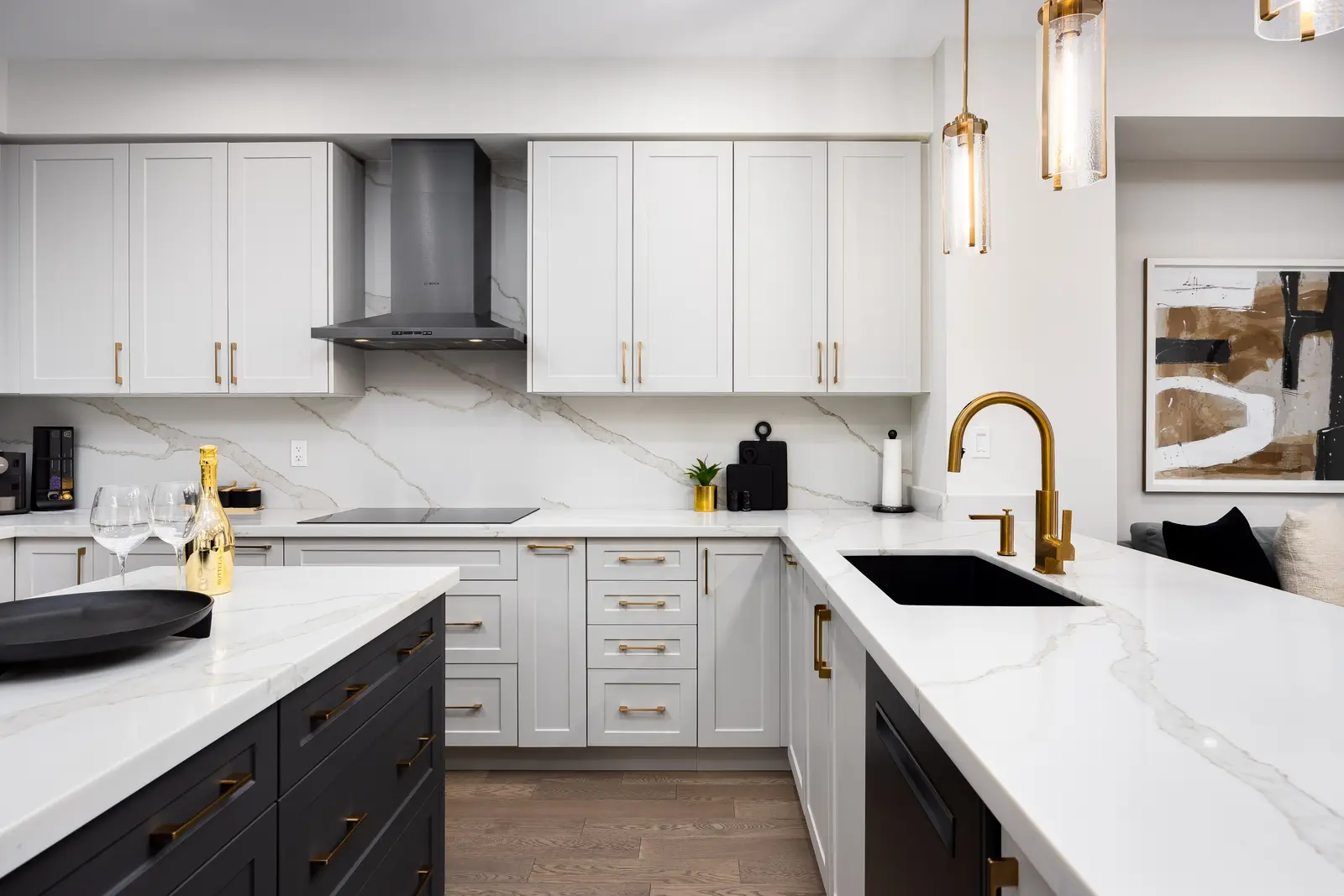 White shaker kitchen in a Richmond Hill townhouse, with a dark island, marble counters, and gold faucet and pendants