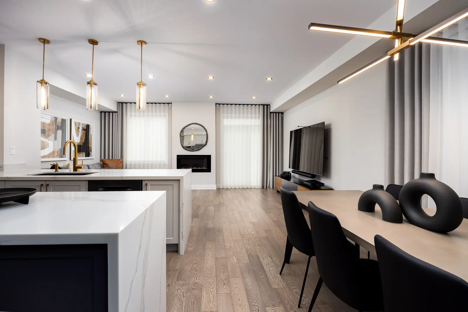 Open kitchen and dining area in a Richmond Hill townhouse, with a gold chandelier and black dining chairs