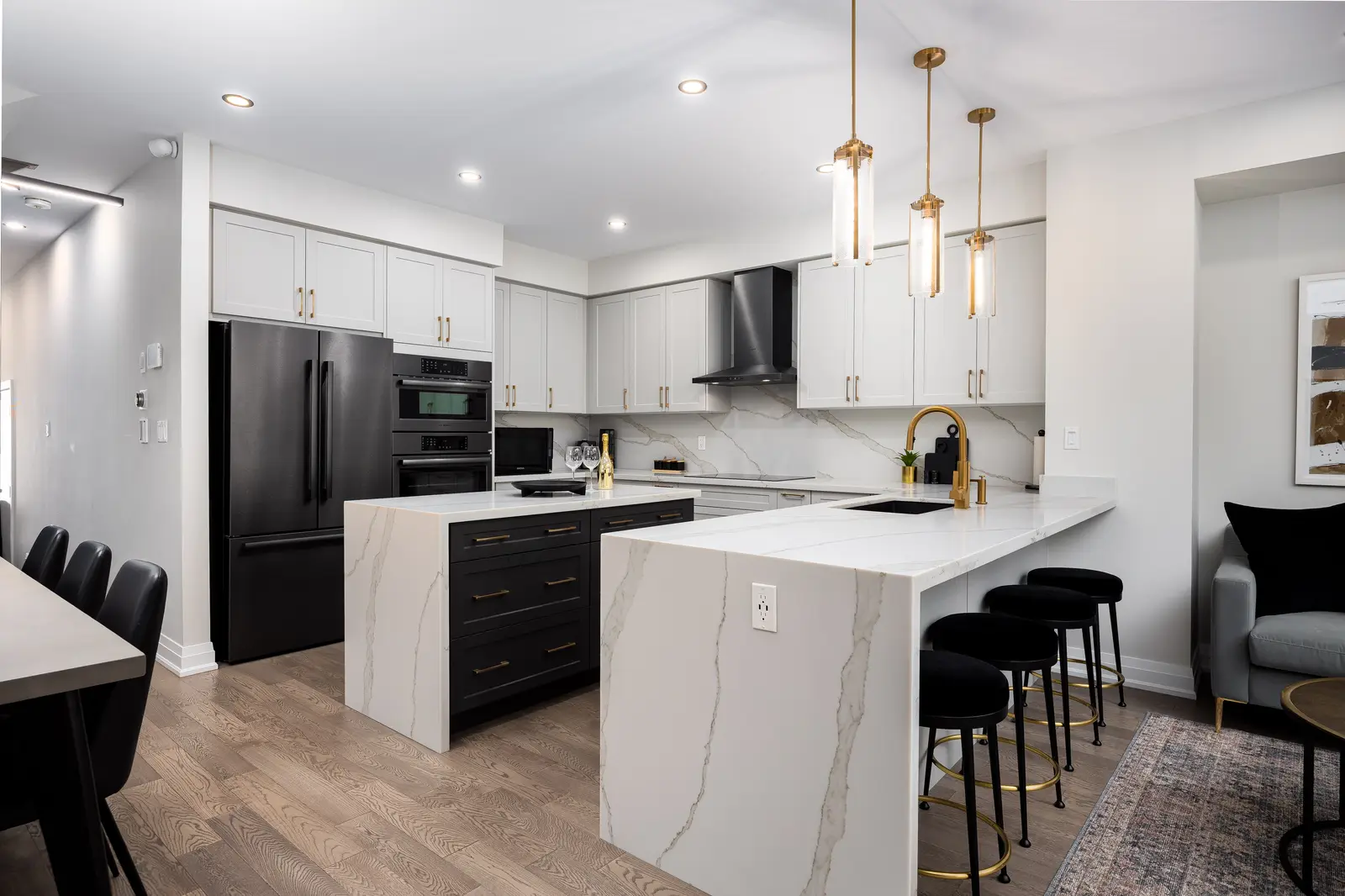 Marble kitchen island in a Richmond Hill townhouse, with black stools, white cabinets, and gold pendants