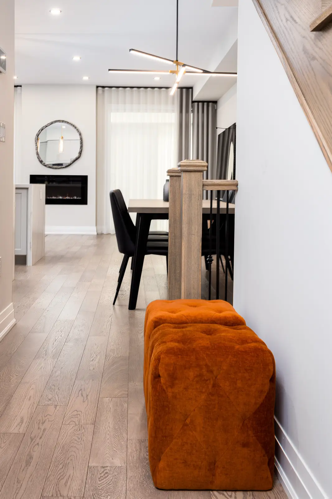 Stair landing in a Richmond Hill townhouse, with a view to the dining table and an orange ottoman