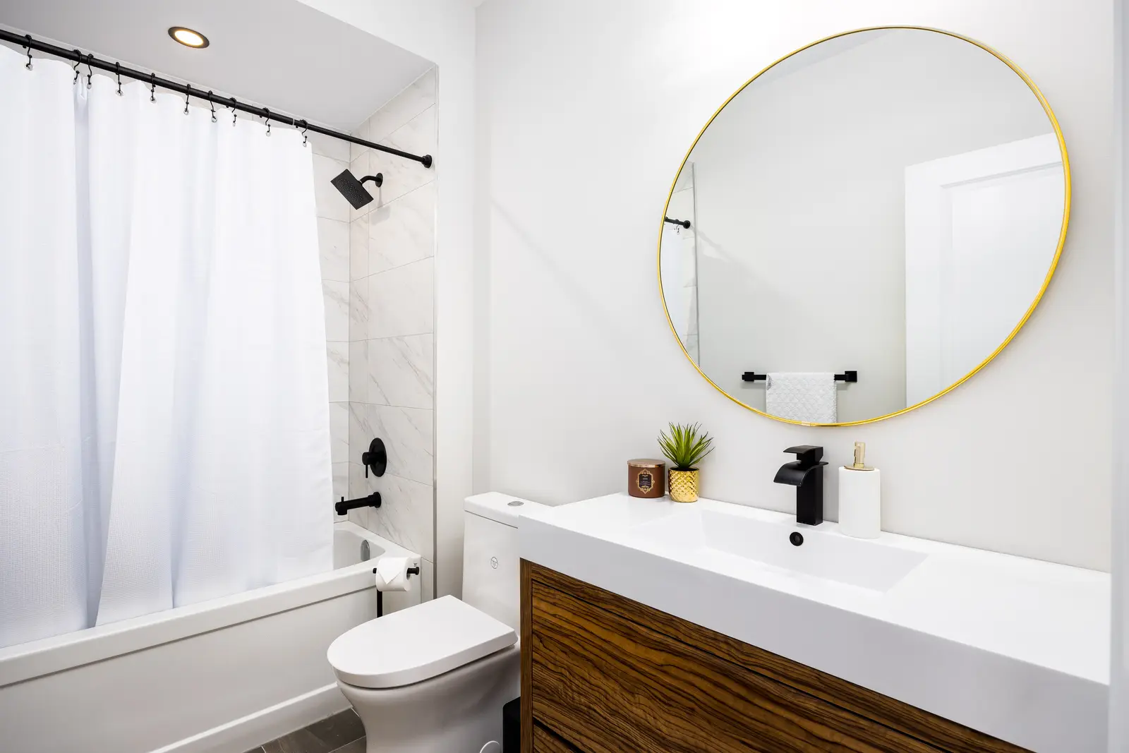 Bathroom in a Richmond Hill townhouse, with a white tub, a shower curtain, and a marble wall