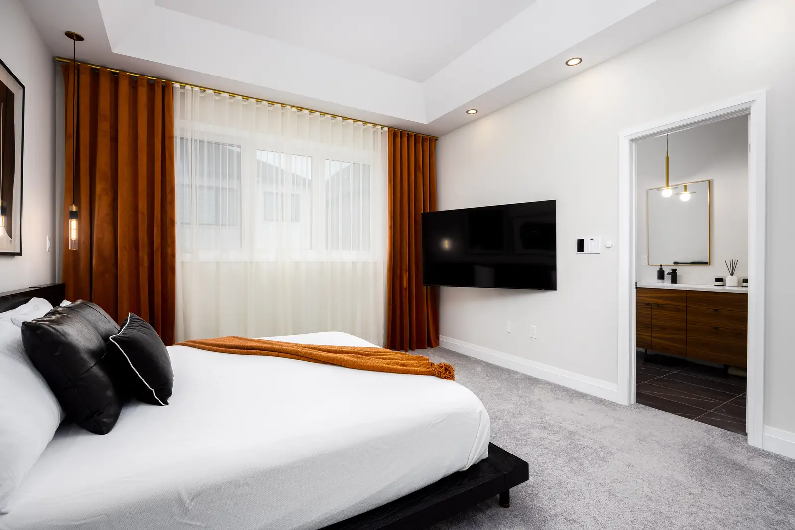 Bedroom in a Richmond Hill townhouse looking toward the ensuite, with mustard curtains and a black bed