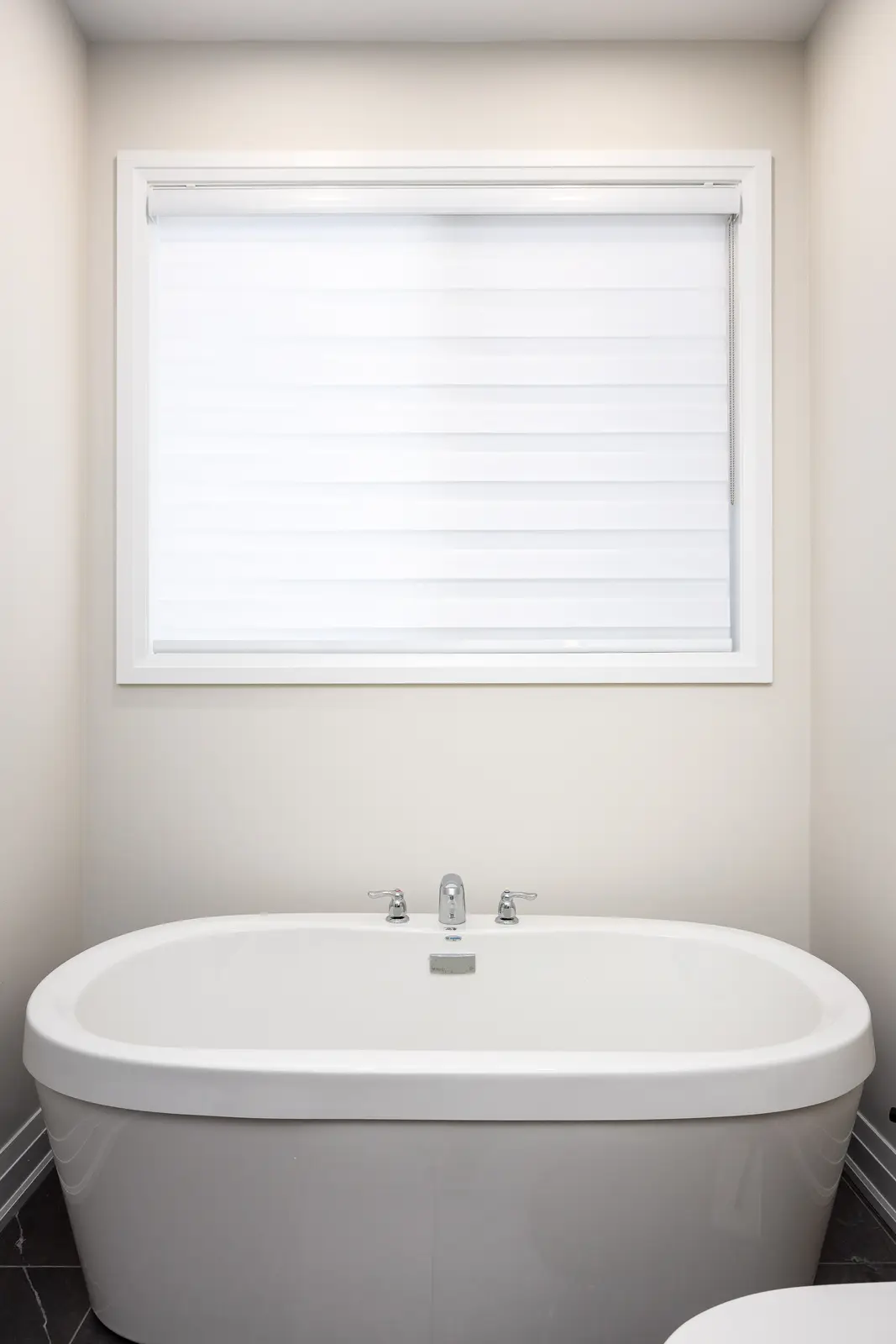 Freestanding white tub in a Richmond Hill townhouse bathroom, beside a window