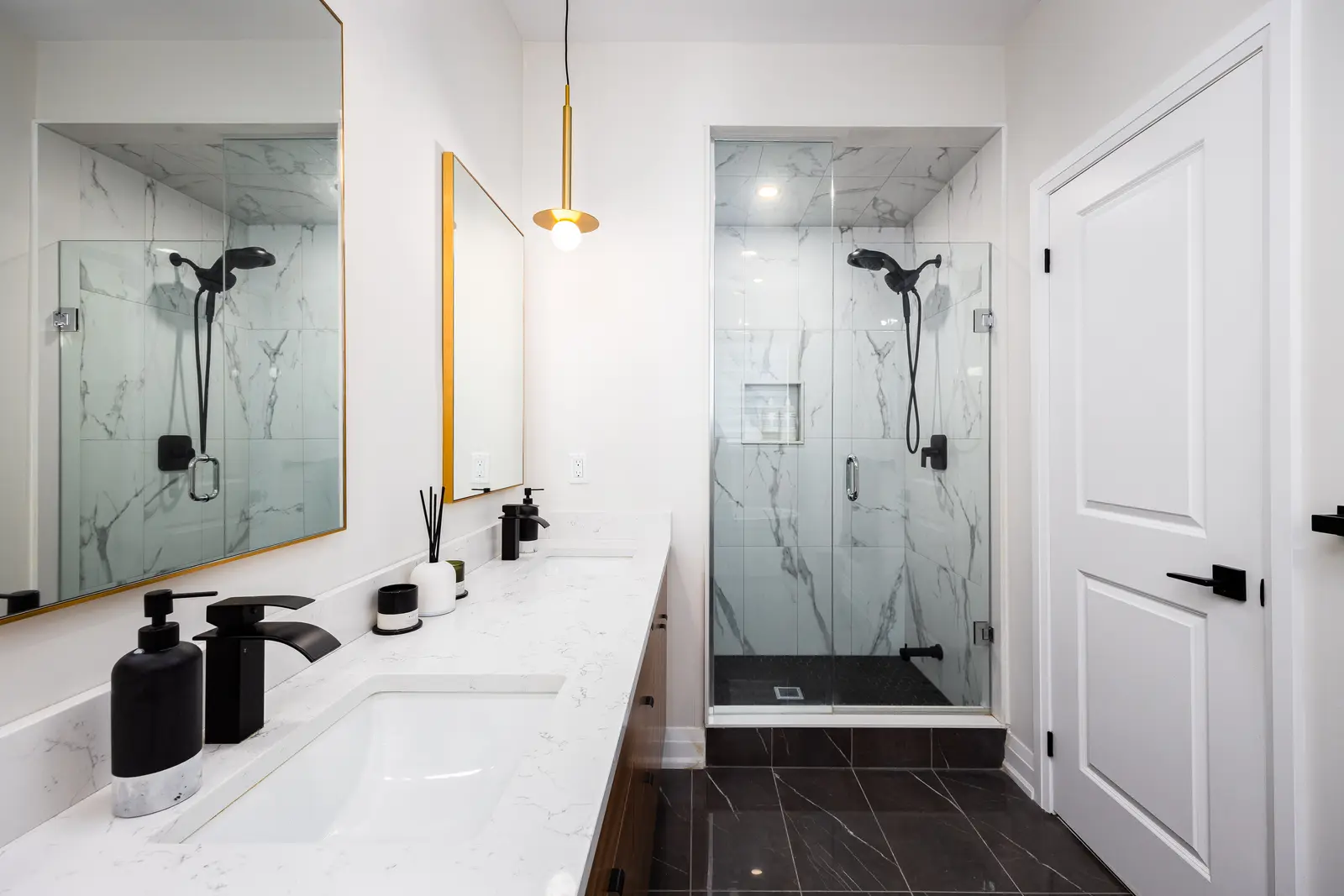 Bathroom in a Richmond Hill townhouse, with a marble vanity, a gold pendant, and a glass shower
