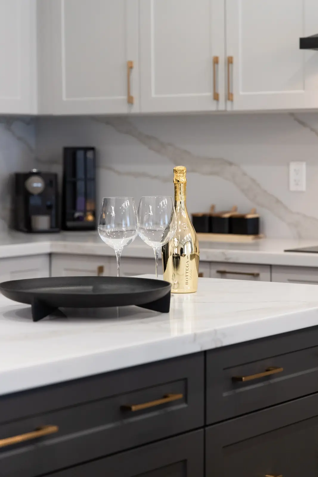 Marble kitchen counter in a Richmond Hill townhouse, with dark lower cabinets, wine glasses, and a gold bottle