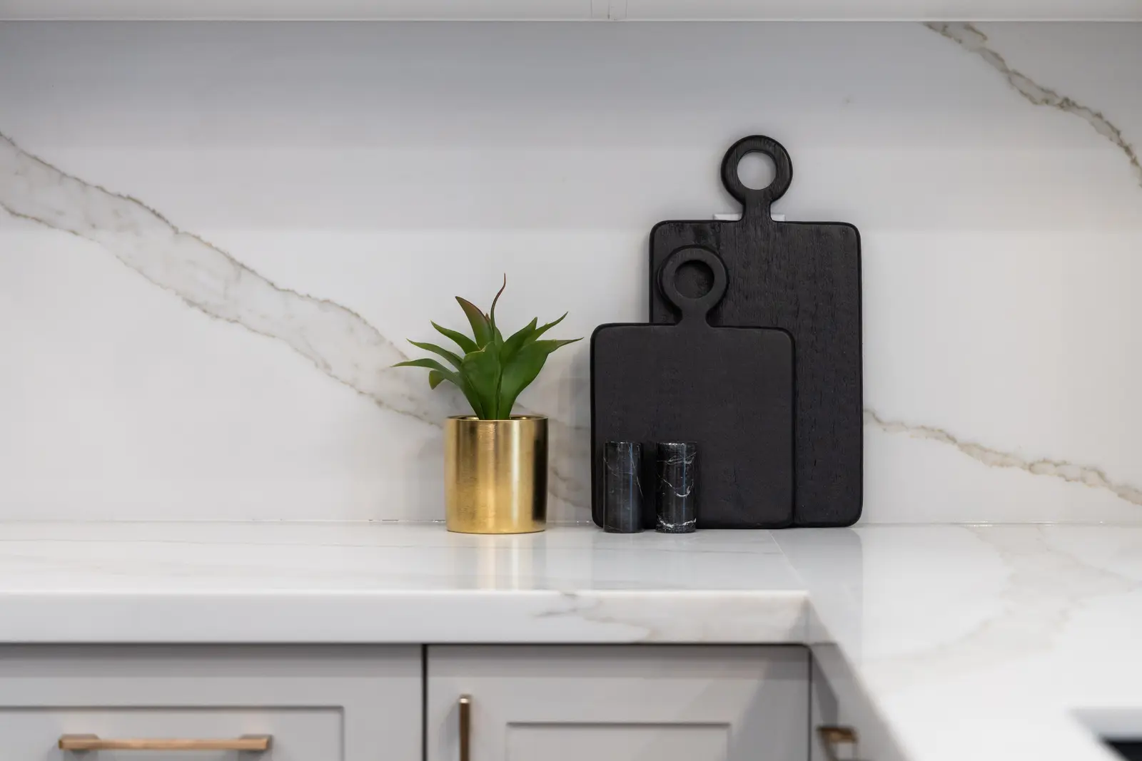 Marble kitchen backsplash in a Richmond Hill townhouse, with black cutting boards and a gold planter