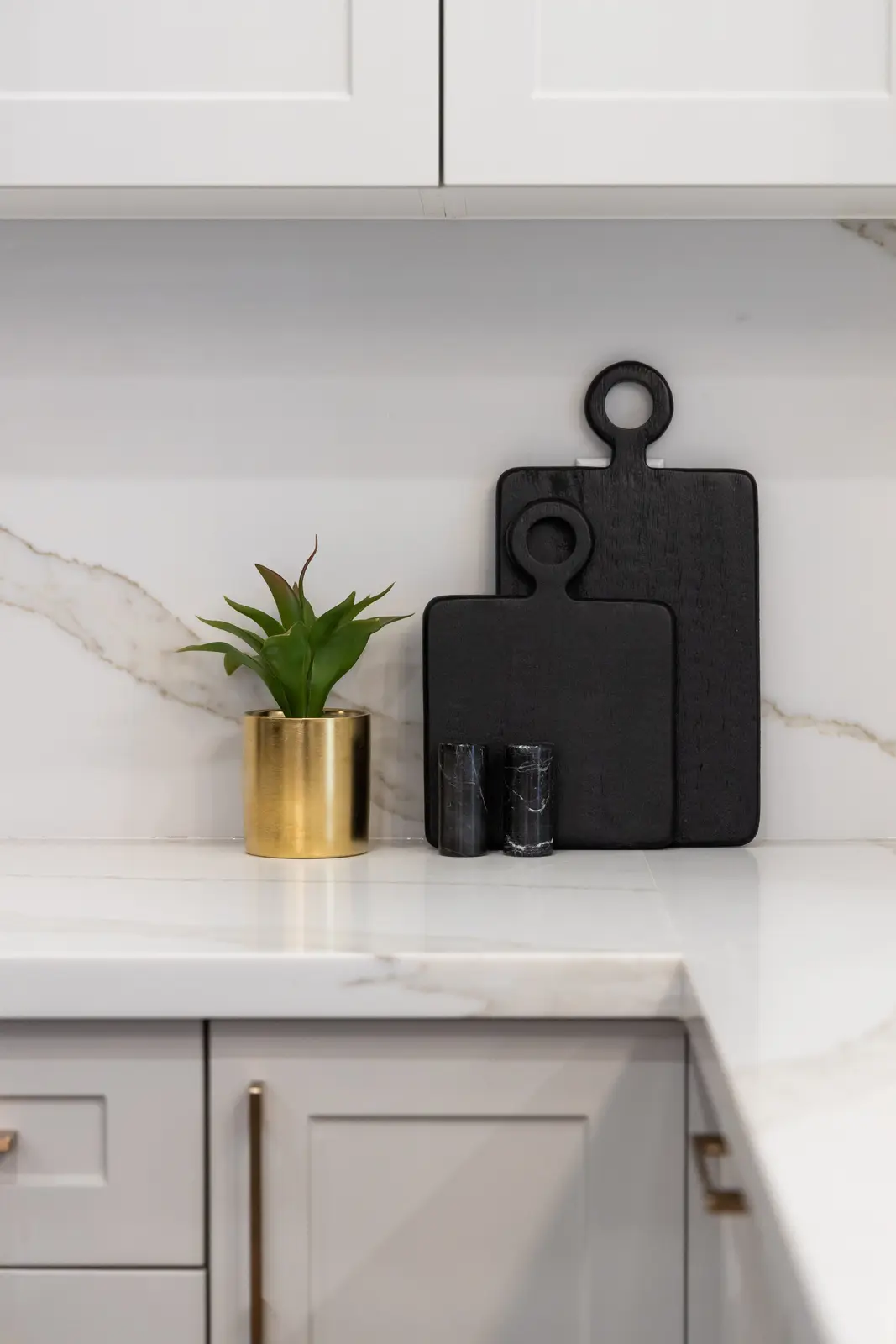 Marble kitchen corner in a Richmond Hill townhouse, with black cutting boards and a gold planter