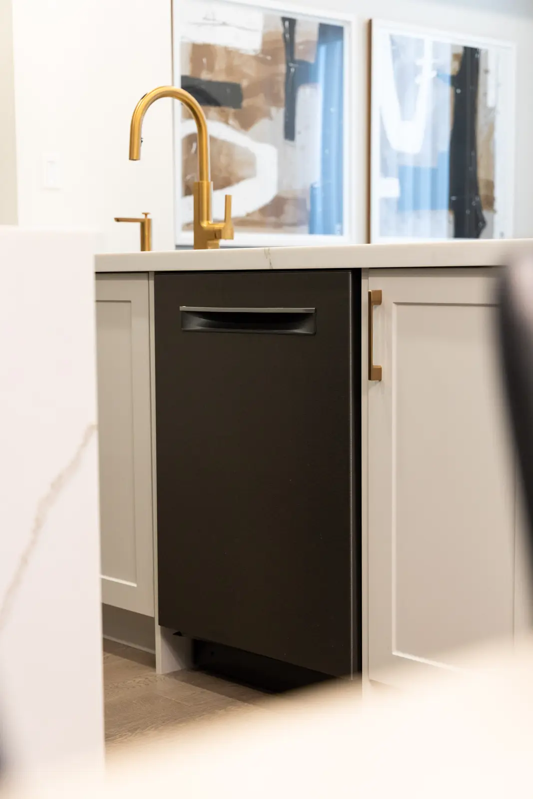 Dark dishwasher beside the marble island and gold faucet in a Richmond Hill townhouse kitchen