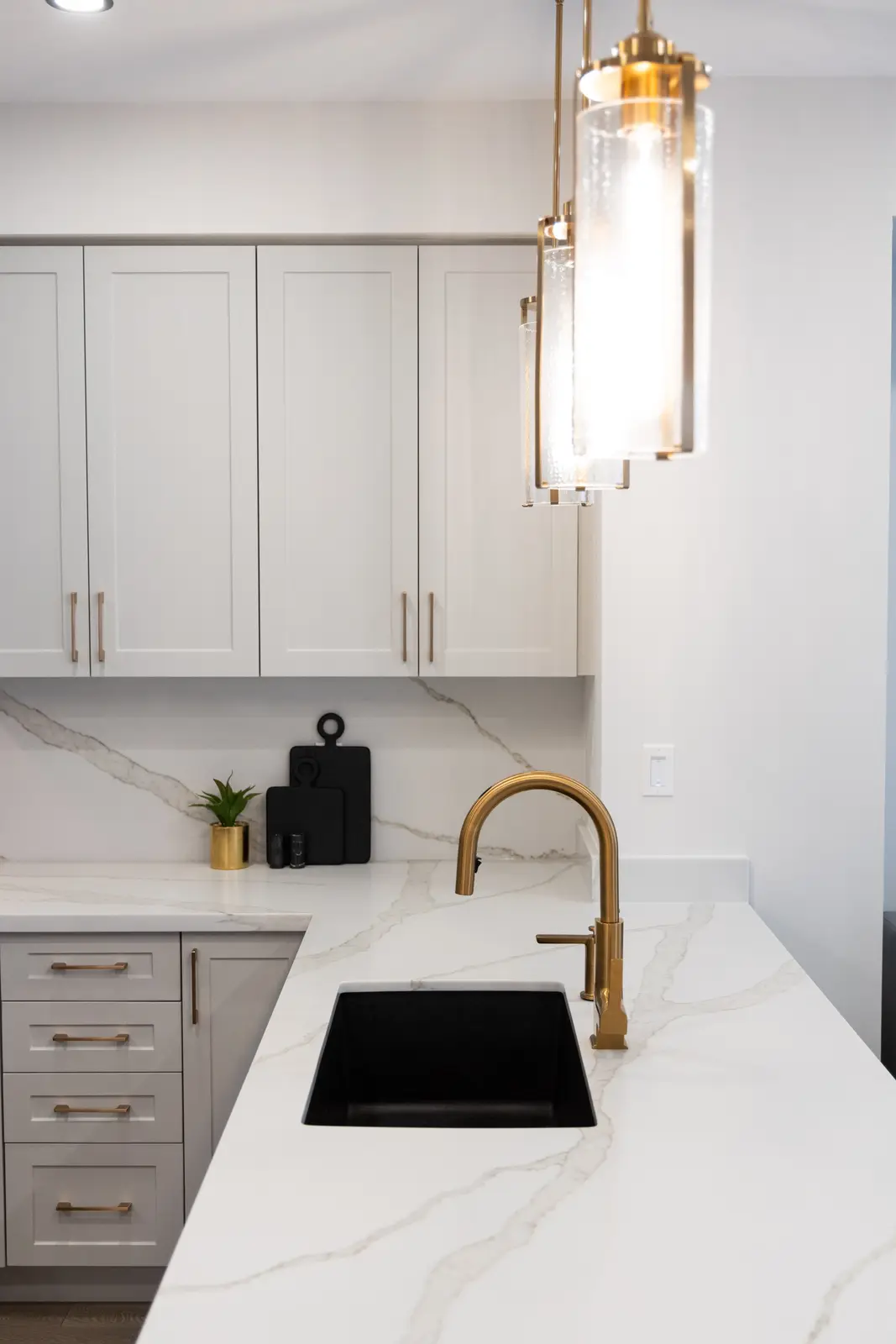 Marble island sink in a Richmond Hill townhouse, with a gold faucet and a glass pendant