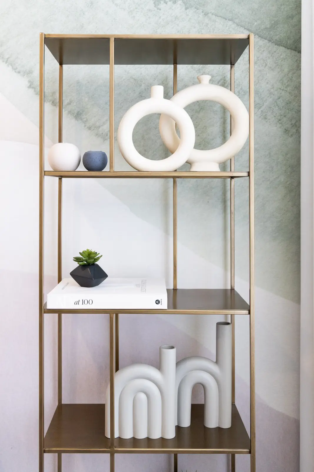 Brass etagere with white ceramics against a green mural in a Richmond Hill townhouse