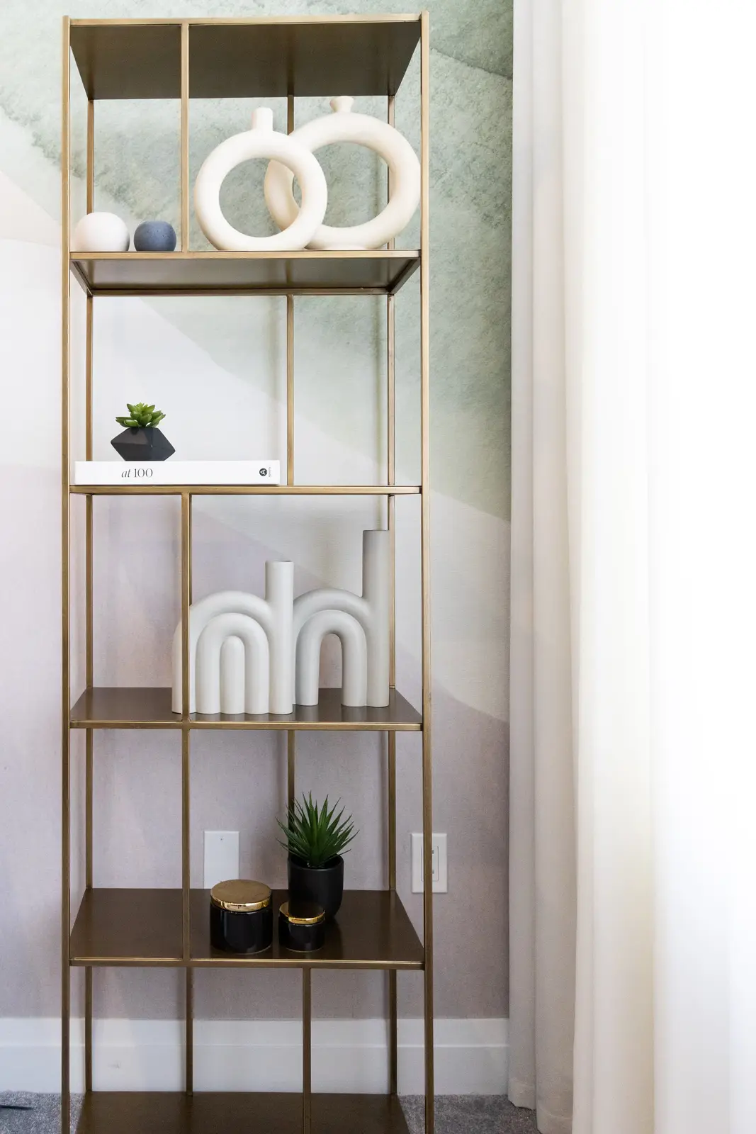 Brass shelf with white ceramics and a green mural in a Richmond Hill townhouse