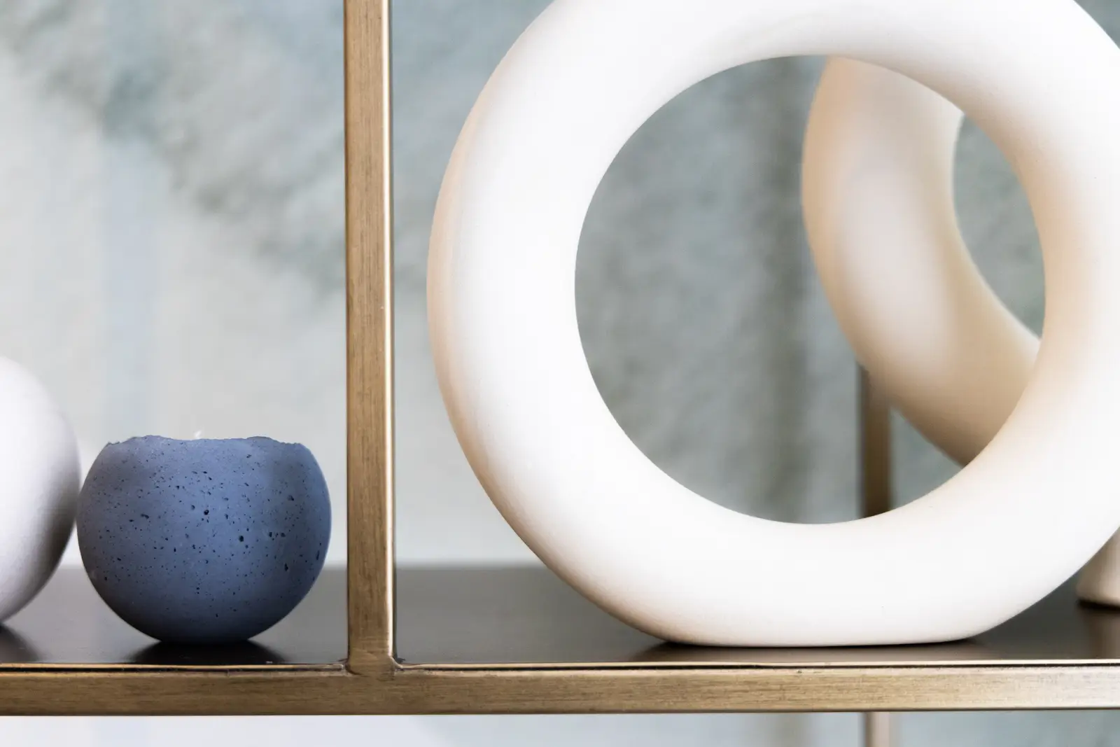 White ceramic ring and a blue bowl on a brass shelf in a Richmond Hill townhouse