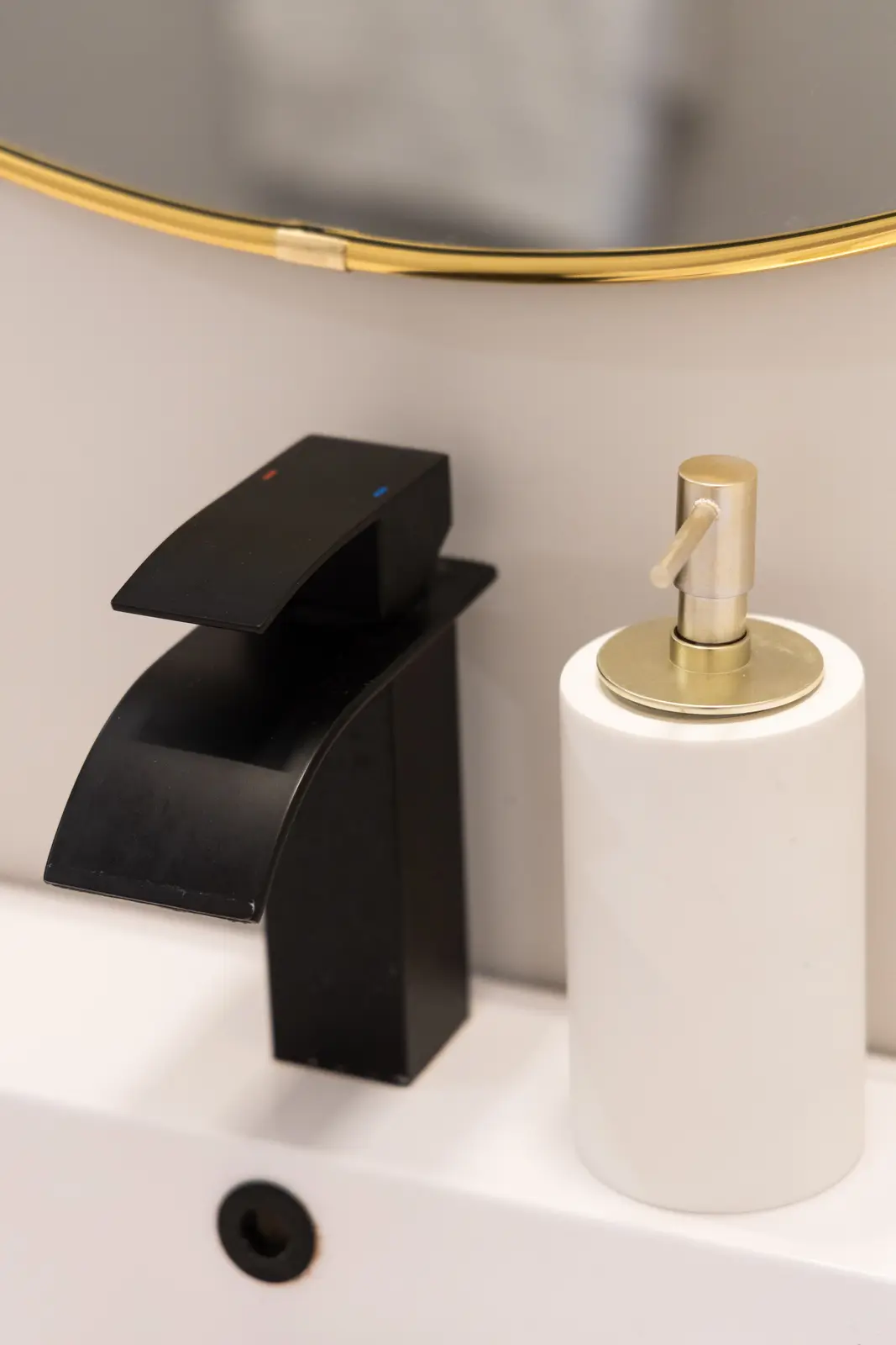 Black faucet and white soap dispenser on the marble vanity in a Richmond Hill townhouse
