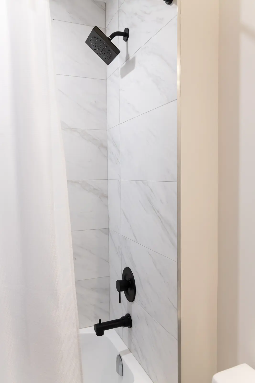 Marble shower wall with black fittings in a Richmond Hill townhouse