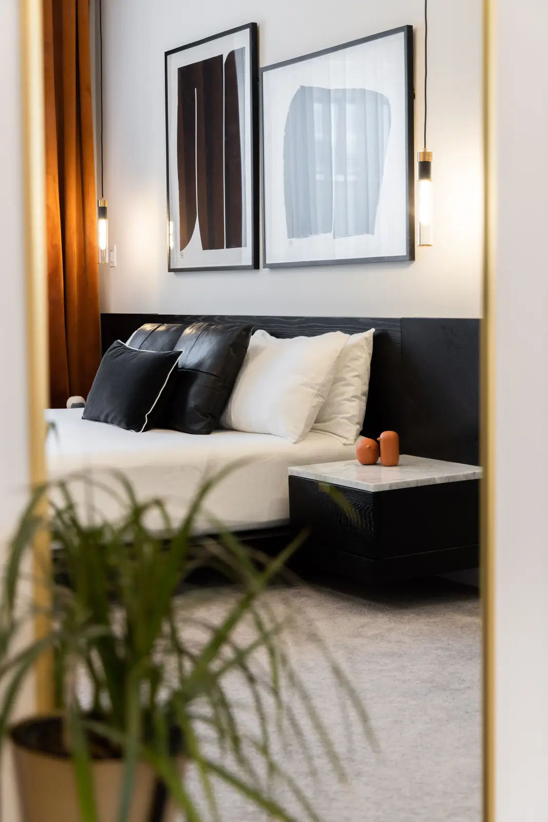 Bedroom in a Richmond Hill townhouse reflected in a mirror, with mustard curtains and a black bed