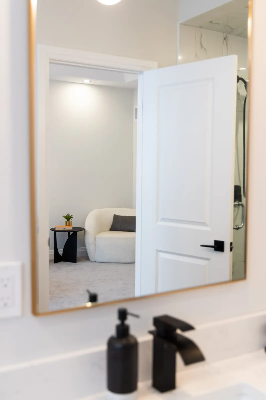 Gold-framed mirror reflecting the bedroom from the bathroom in a Richmond Hill townhouse