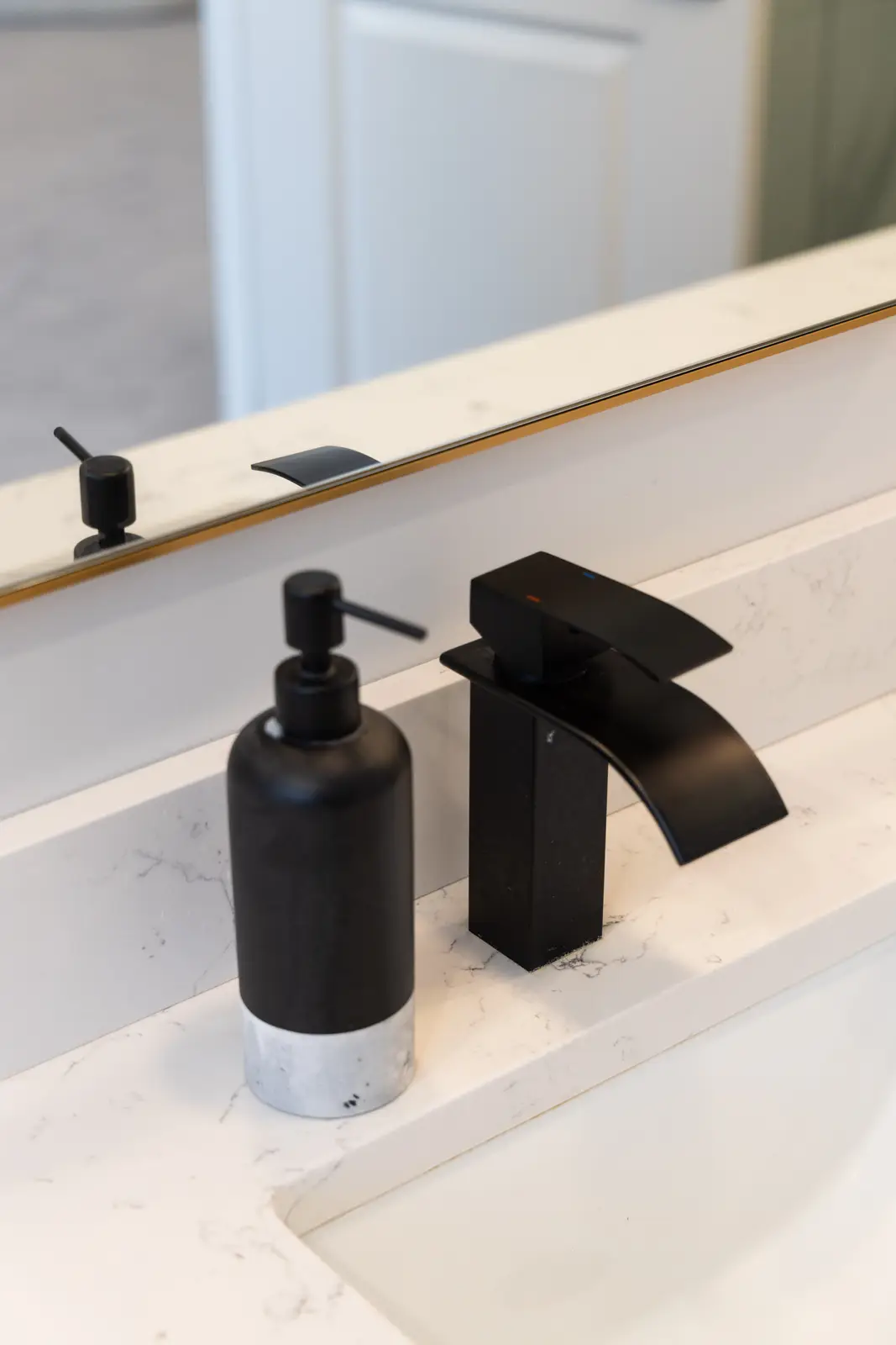 Black faucet and soap dispenser on the marble vanity in a Richmond Hill townhouse
