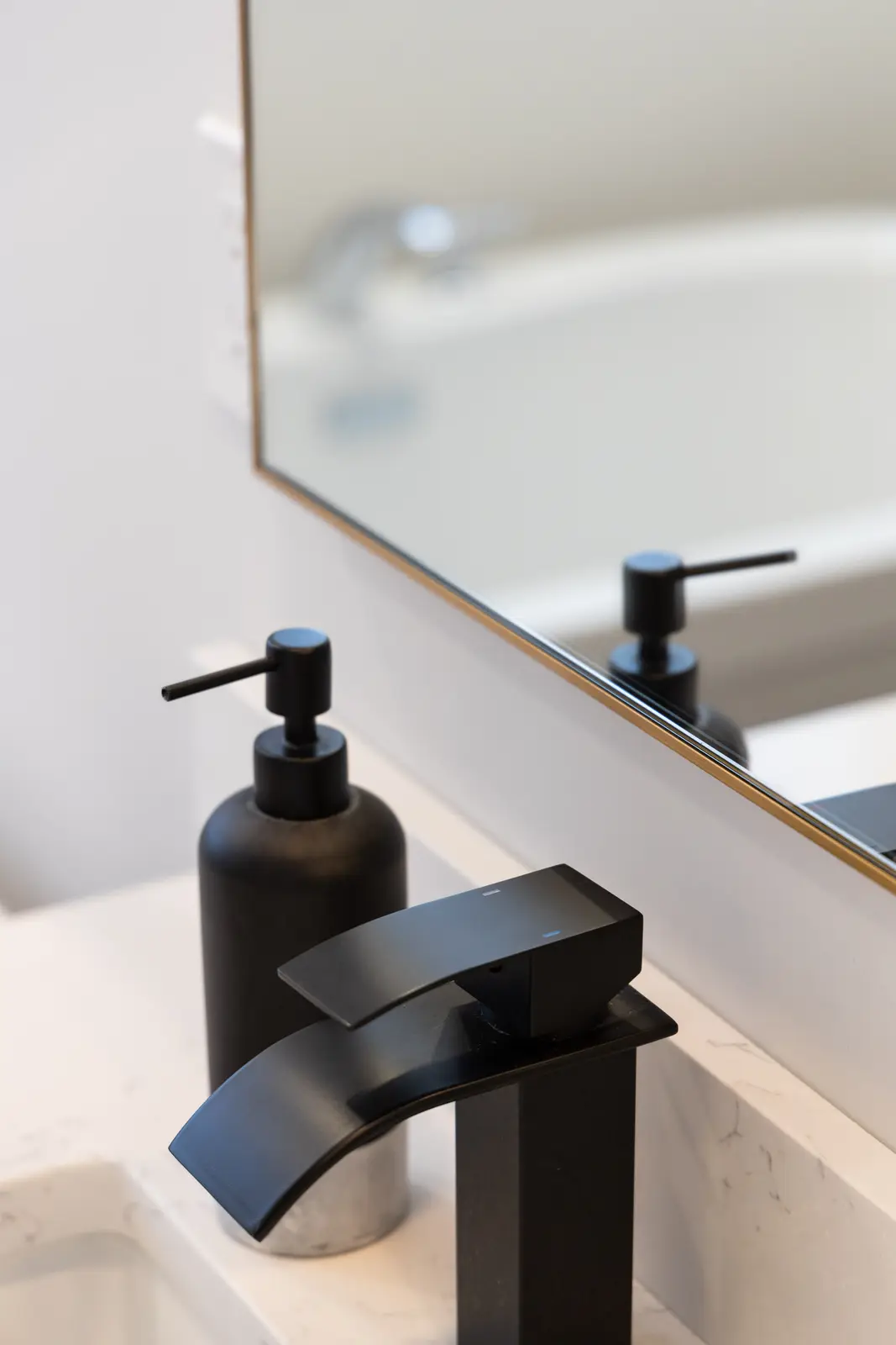 Black faucet on the marble vanity with a gold-framed mirror in a Richmond Hill townhouse