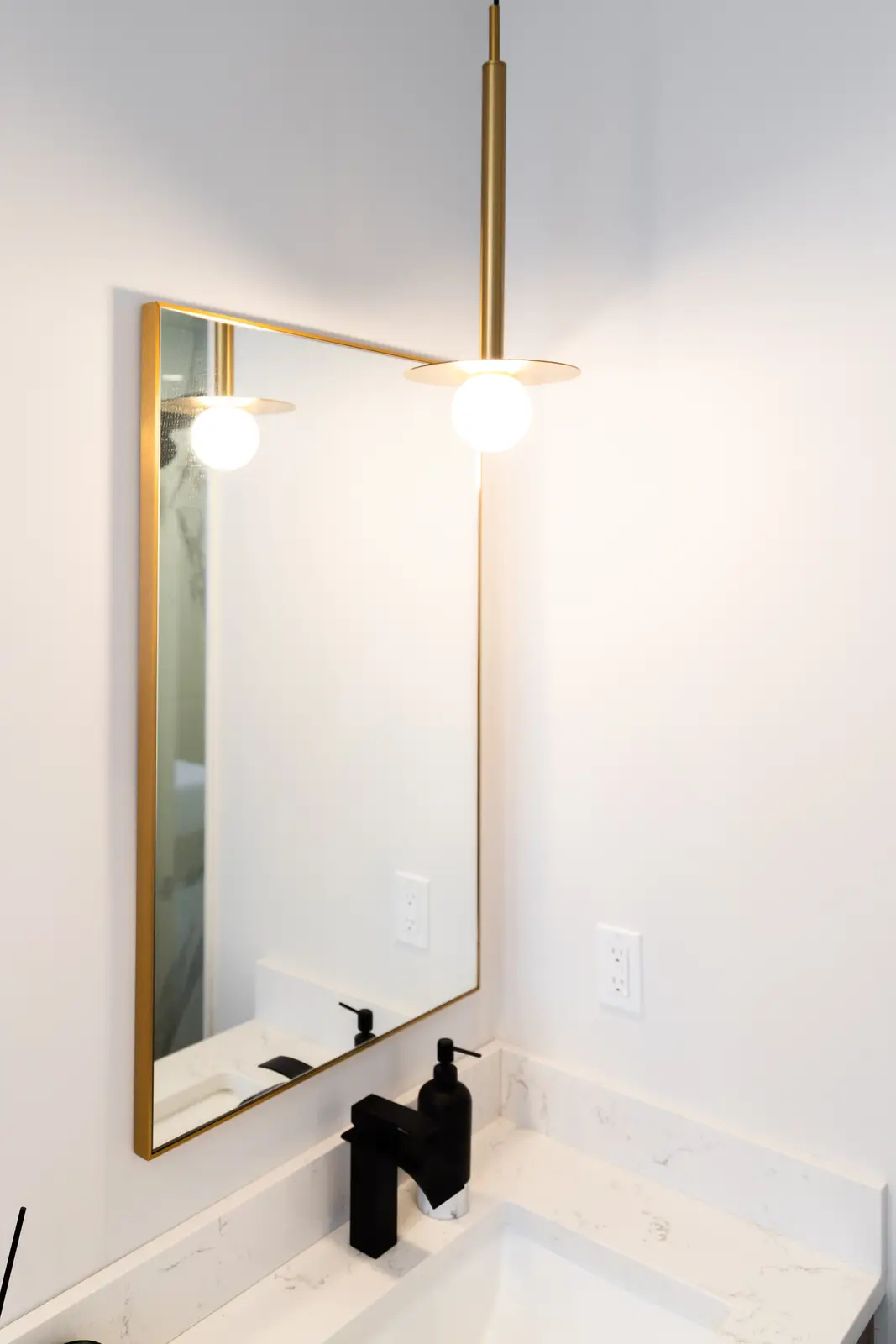 Gold pendant beside a gold-framed bathroom mirror in a Richmond Hill townhouse