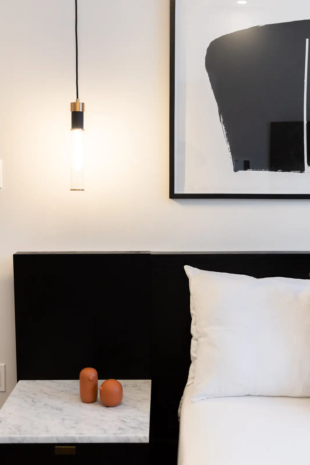 Marble nightstand and glass pendant beside the black bed in a Richmond Hill townhouse