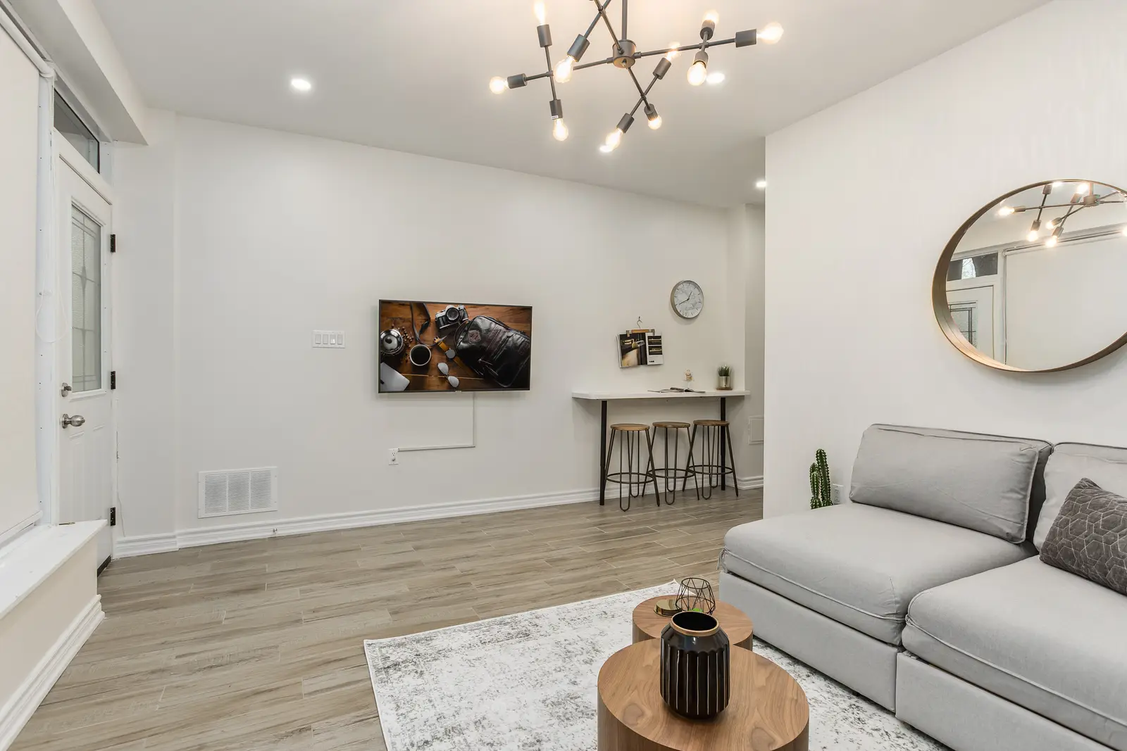 Finished room in a downtown Toronto basement renovation, with white walls, light wood floors, and grey upholstery.