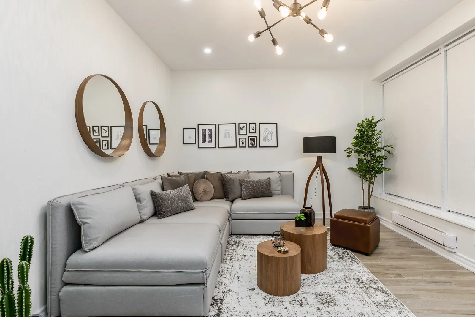 Finished room in a downtown Toronto basement renovation, with white walls, light wood floors, and grey upholstery.