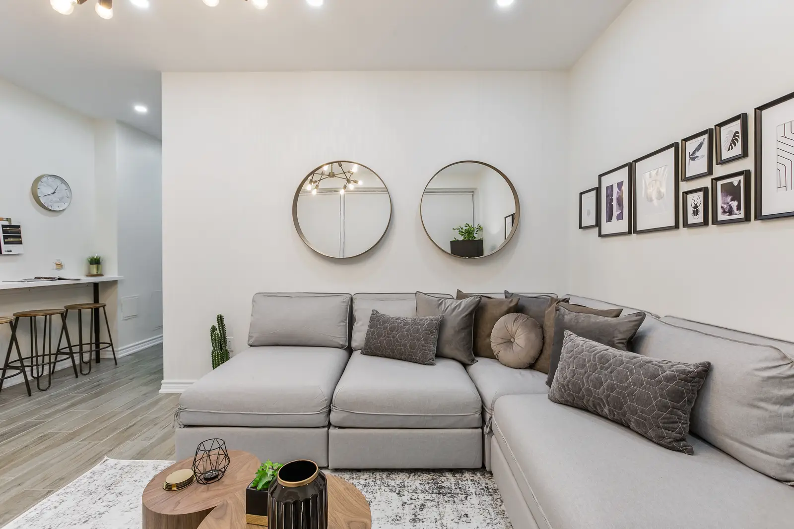 Finished room in a downtown Toronto basement renovation, with white walls, light wood floors, and grey upholstery.