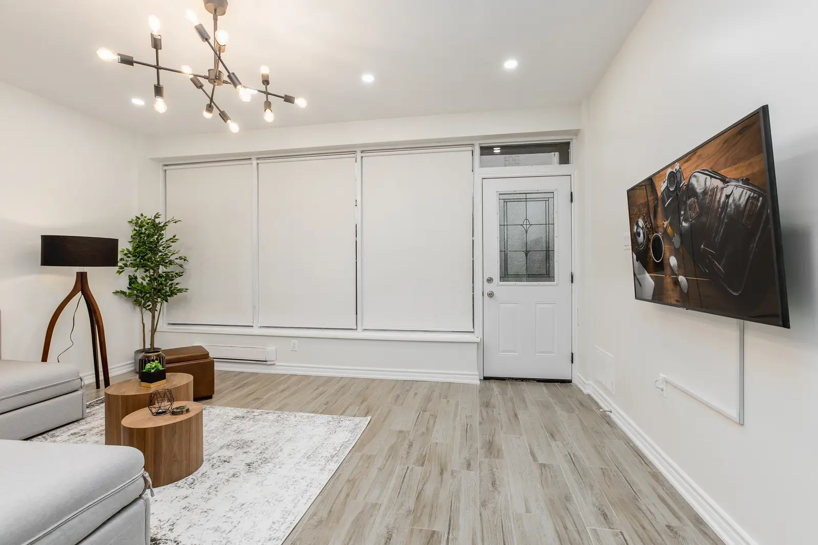 Finished room in a downtown Toronto basement renovation, with white walls, light wood floors, and grey upholstery.
