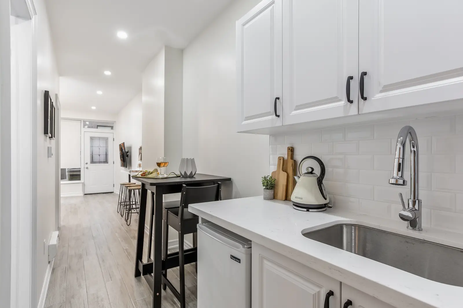 Finished room in a downtown Toronto basement renovation, with white walls, light wood floors, and grey upholstery.