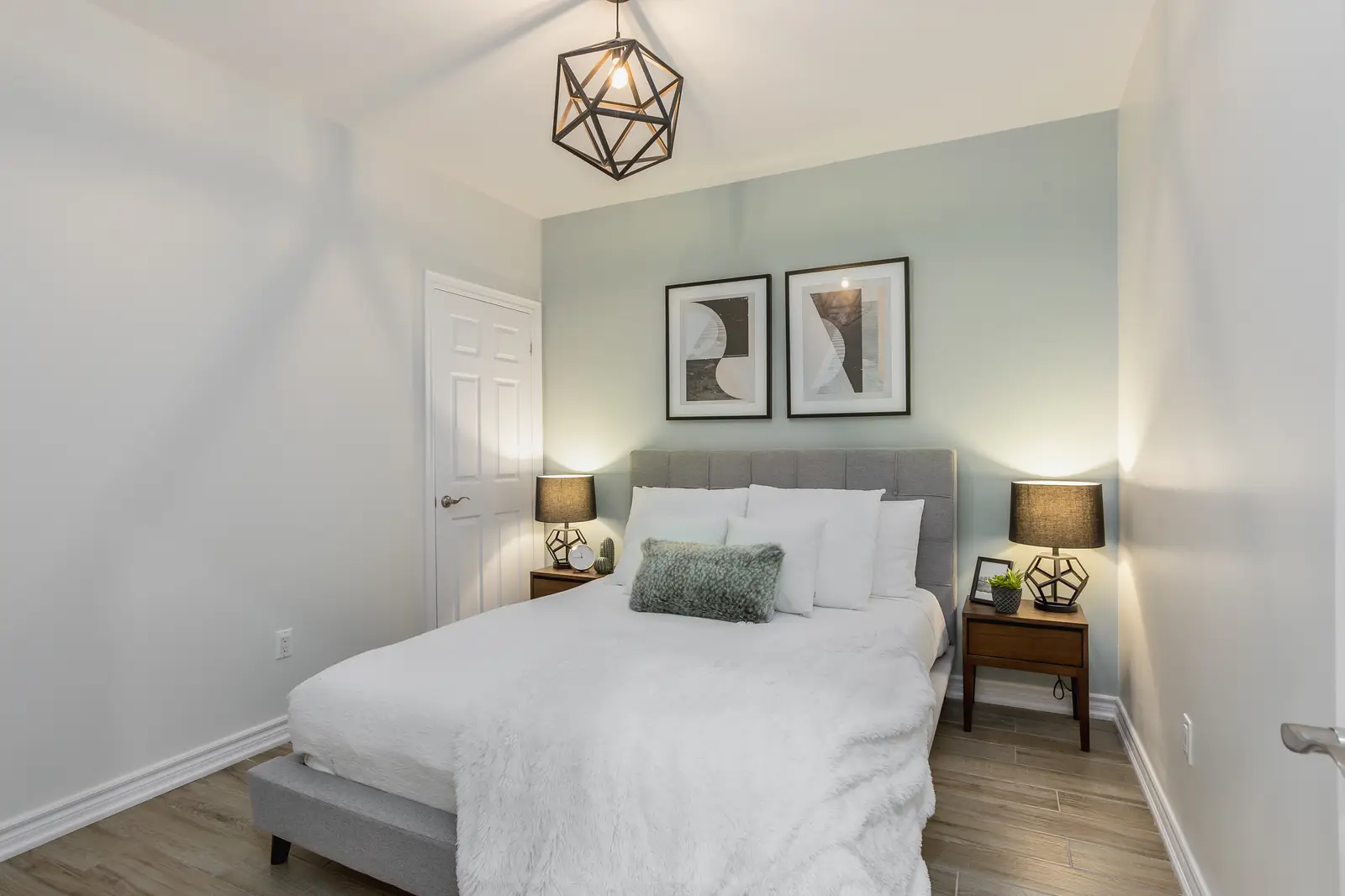Finished room in a downtown Toronto basement renovation, with white walls, light wood floors, and grey upholstery.