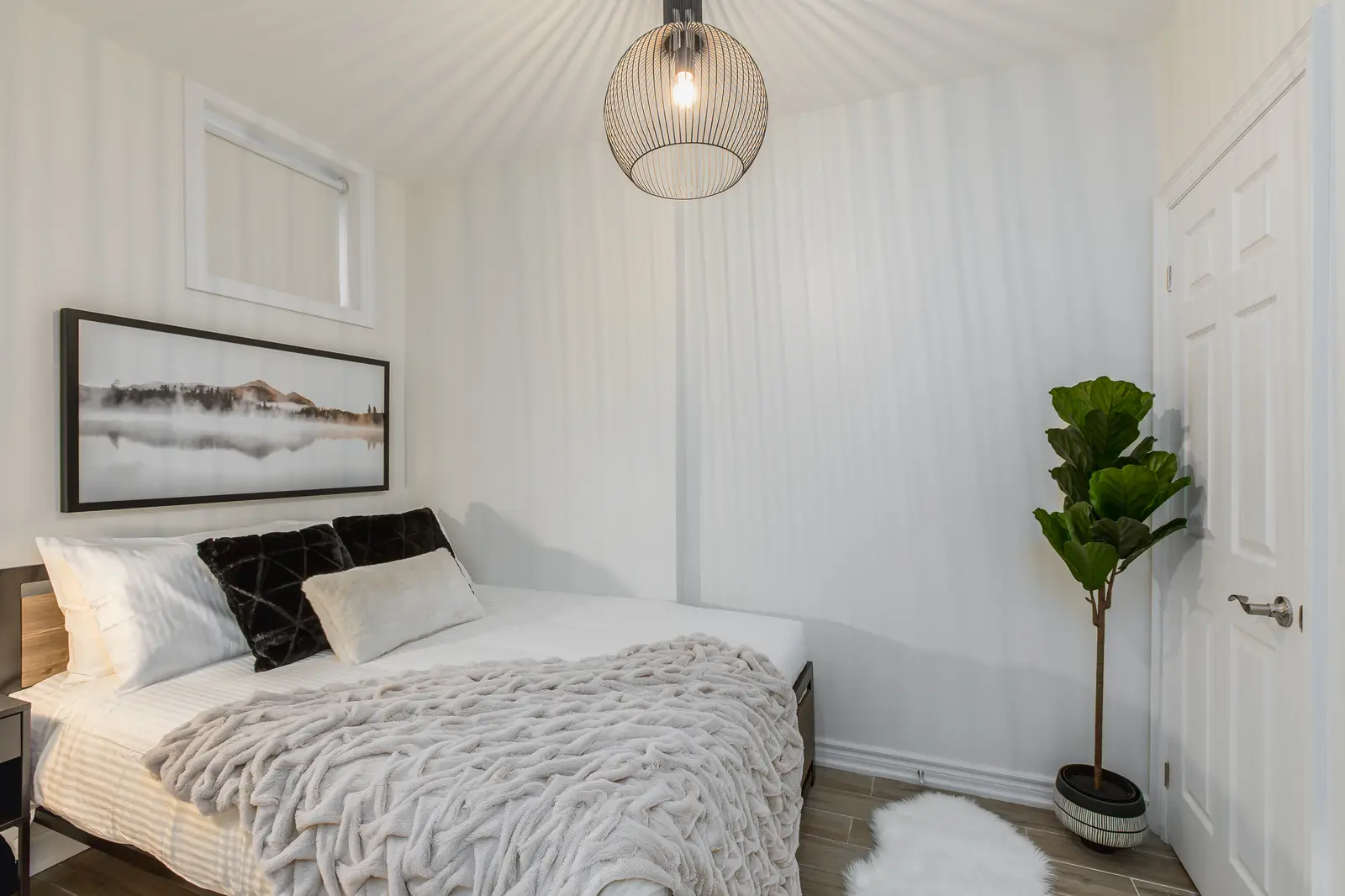Finished room in a downtown Toronto basement renovation, with white walls, light wood floors, and grey upholstery.