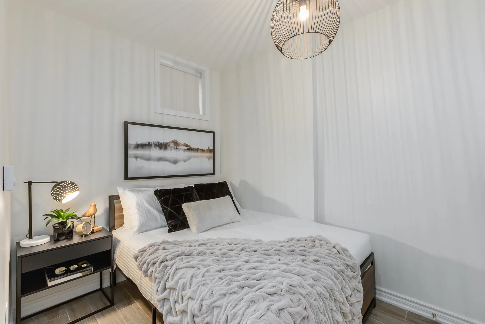 Finished room in a downtown Toronto basement renovation, with white walls, light wood floors, and grey upholstery.