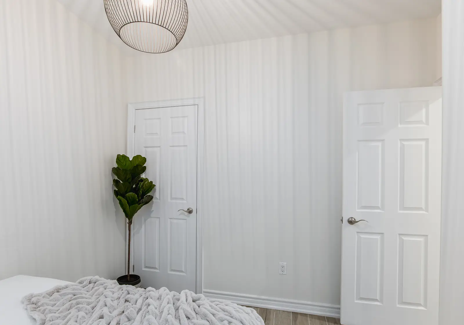 Finished room in a downtown Toronto basement renovation, with white walls, light wood floors, and grey upholstery.
