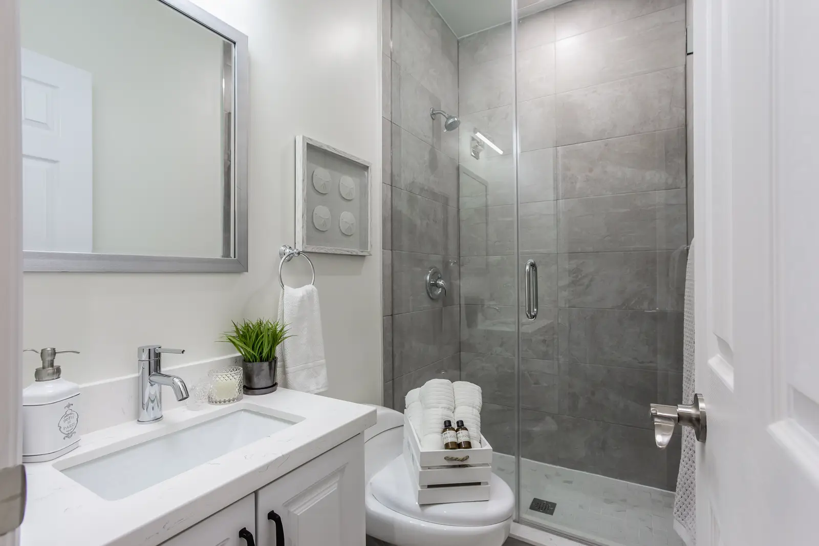 Finished room in a downtown Toronto basement renovation, with white walls, light wood floors, and grey upholstery.