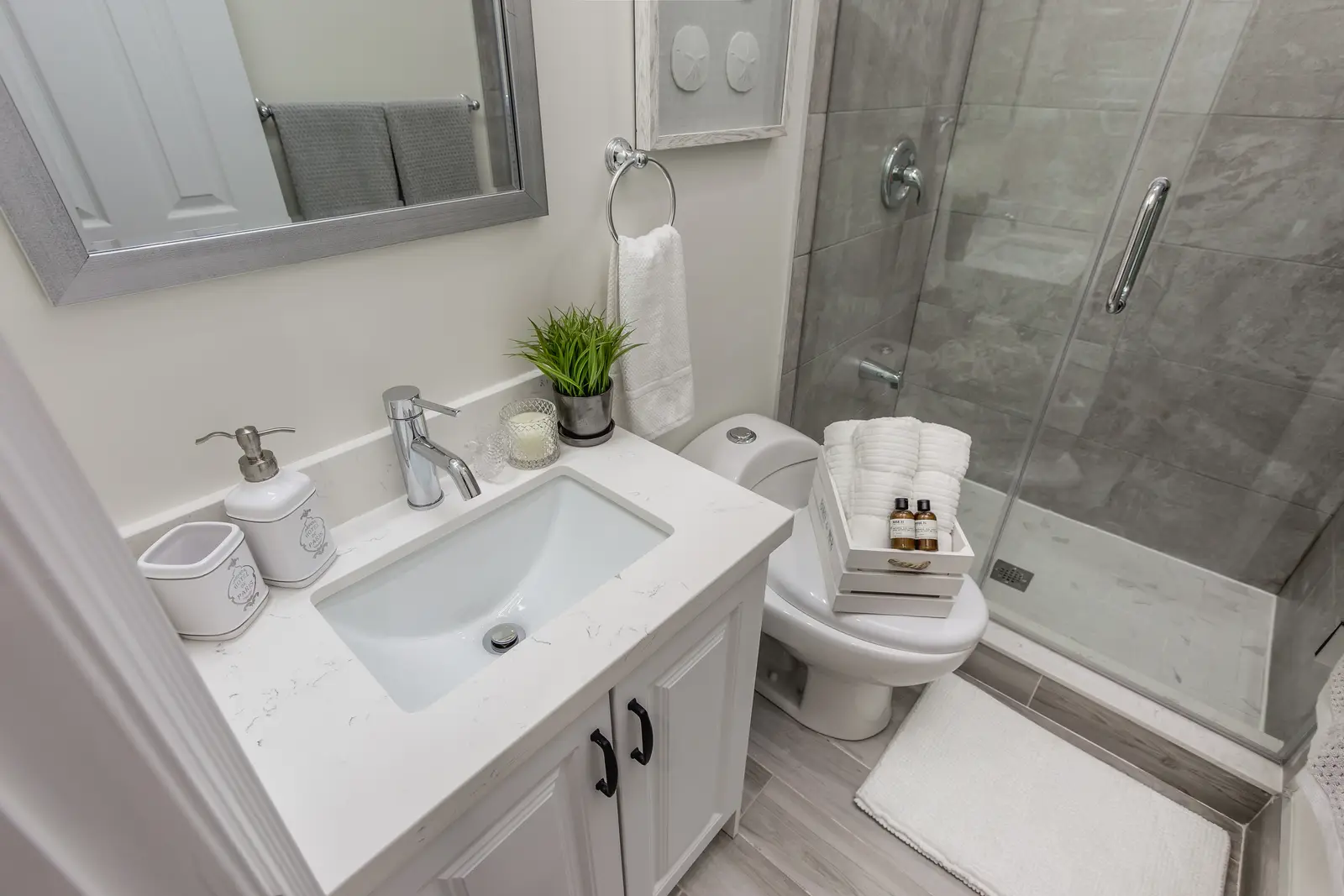 Finished room in a downtown Toronto basement renovation, with white walls, light wood floors, and grey upholstery.