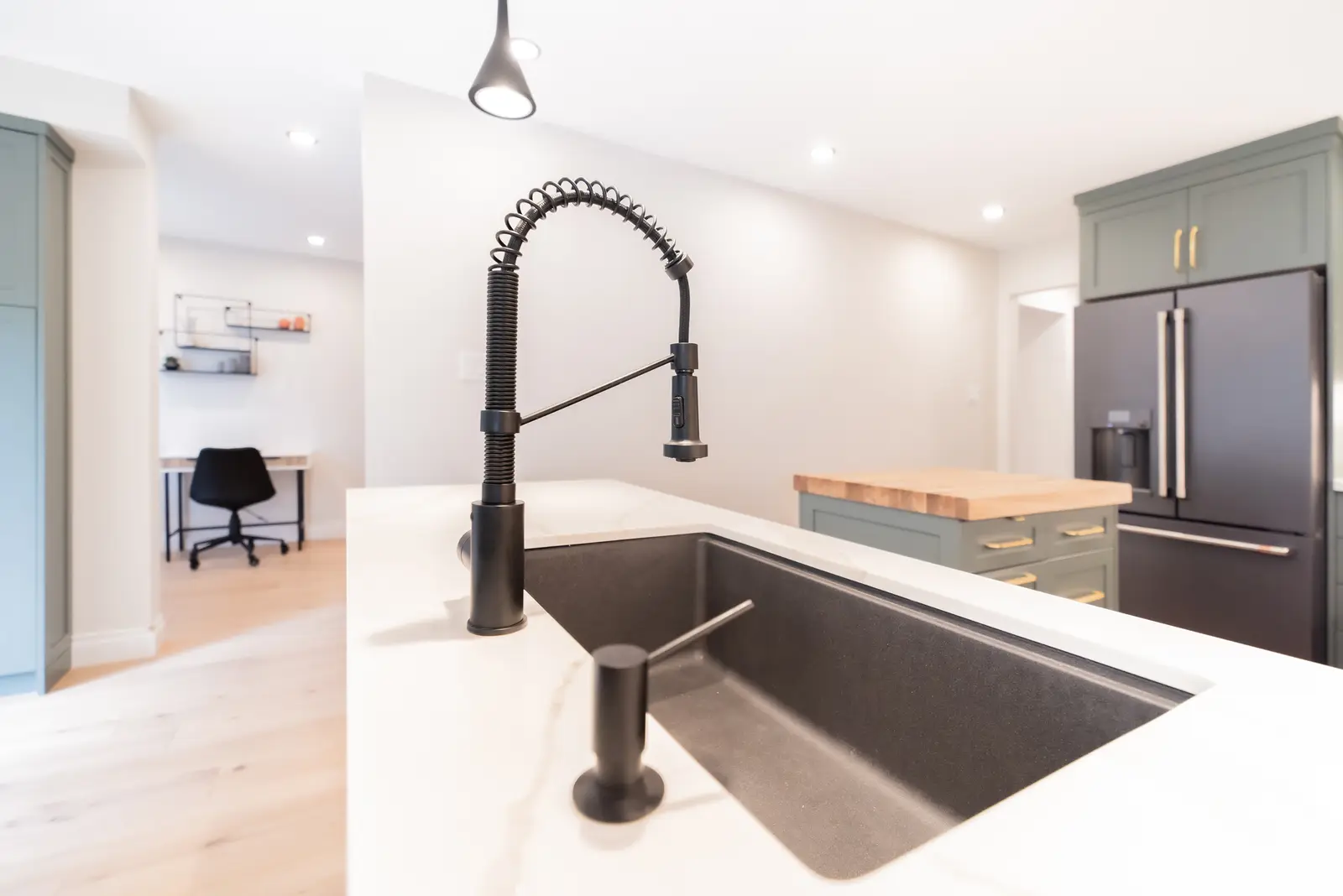 Interior of a Thornhill house renovation, with sage cabinetry, light wood floors, walnut, and brass fittings.