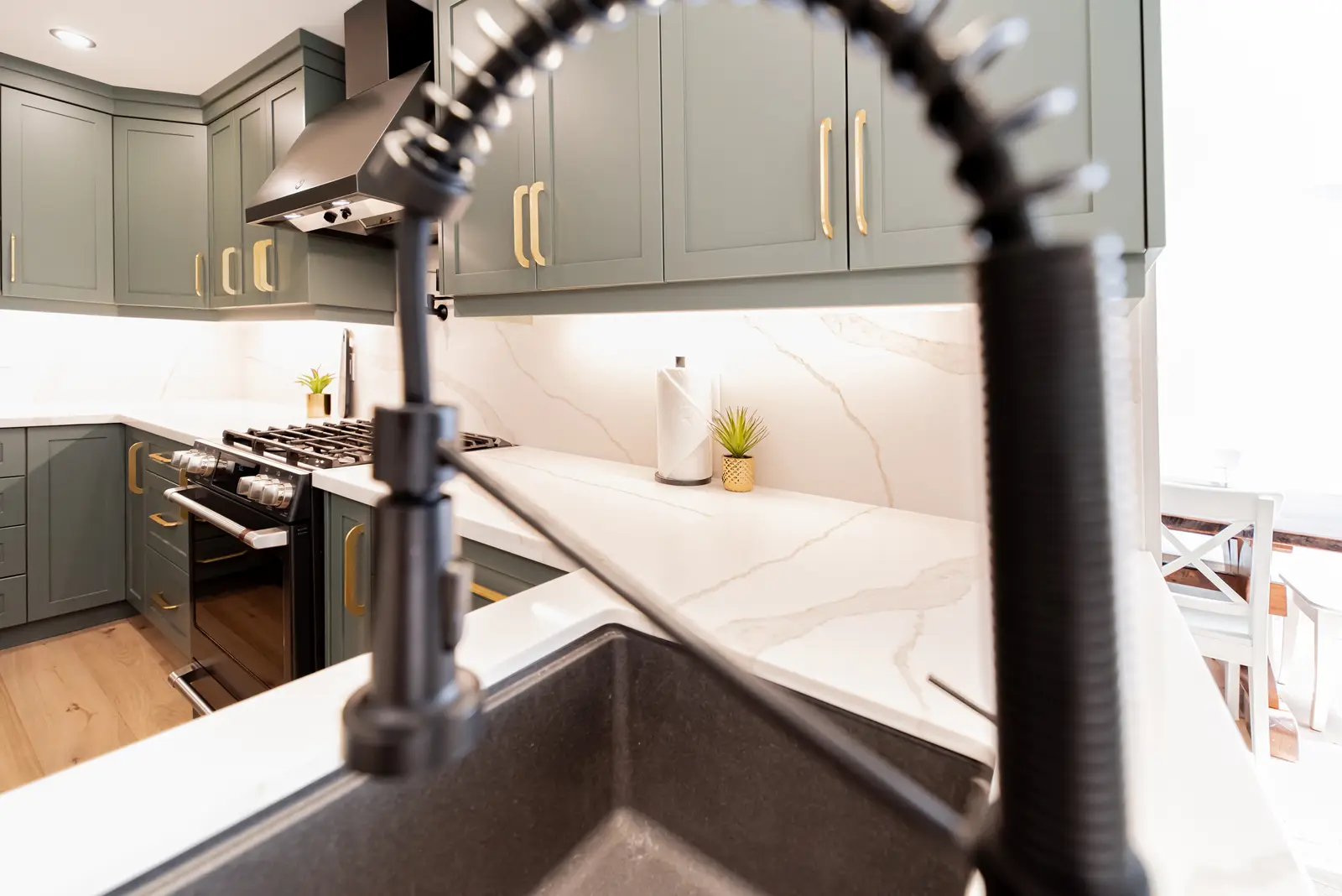 Interior of a Thornhill house renovation, with sage cabinetry, light wood floors, walnut, and brass fittings.