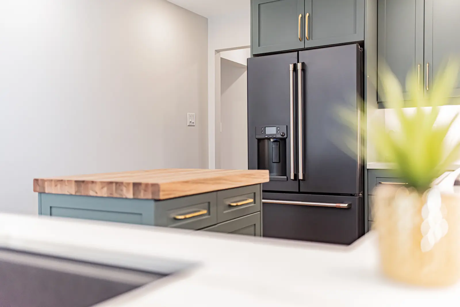 Interior of a Thornhill house renovation, with sage cabinetry, light wood floors, walnut, and brass fittings.