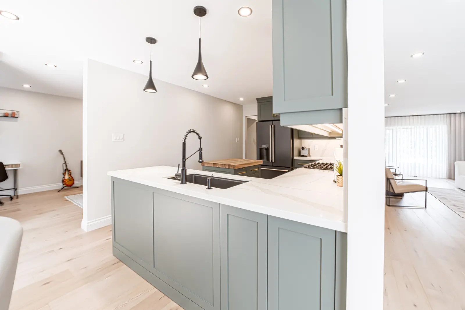 Interior of a Thornhill house renovation, with sage cabinetry, light wood floors, walnut, and brass fittings.