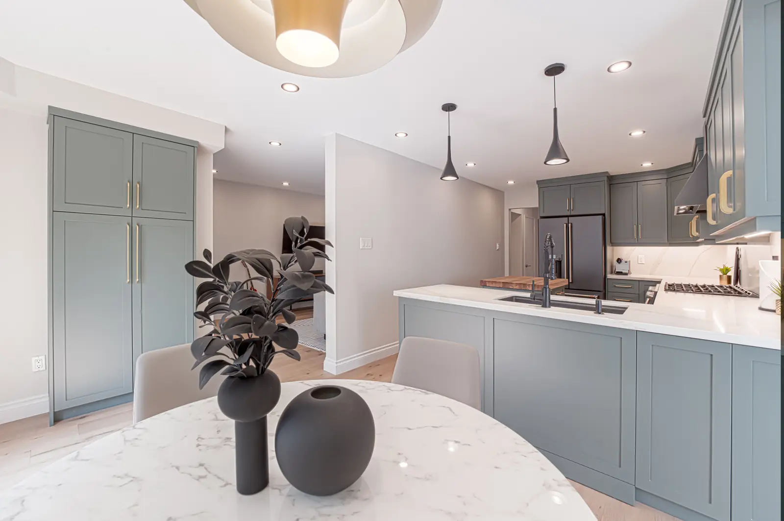 Interior of a Thornhill house renovation, with sage cabinetry, light wood floors, walnut, and brass fittings.