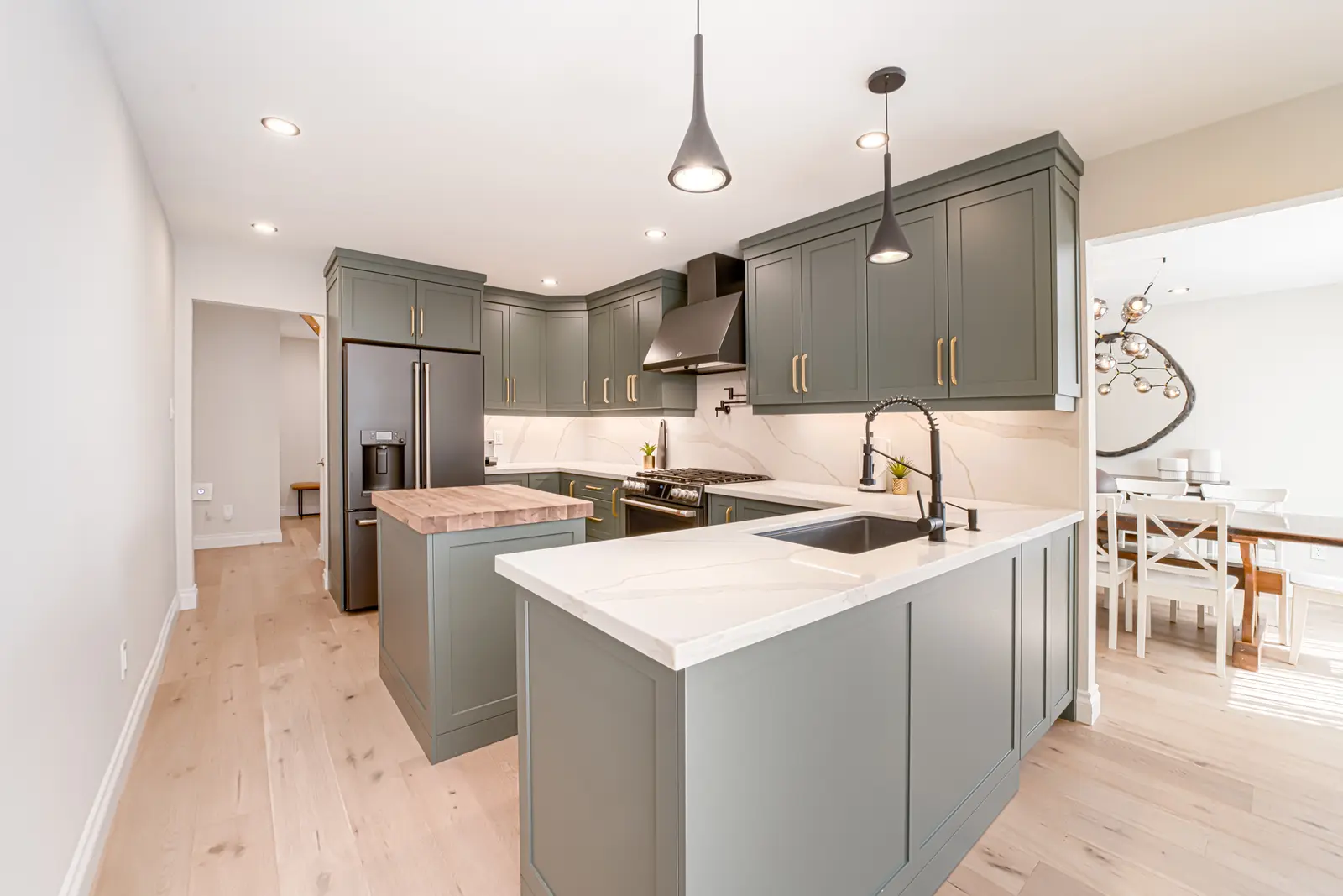Interior of a Thornhill house renovation, with sage cabinetry, light wood floors, walnut, and brass fittings.