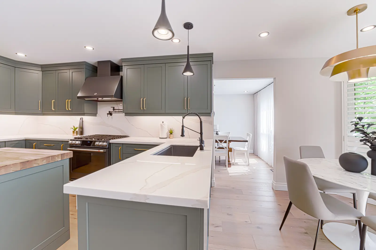 Interior of a Thornhill house renovation, with sage cabinetry, light wood floors, walnut, and brass fittings.