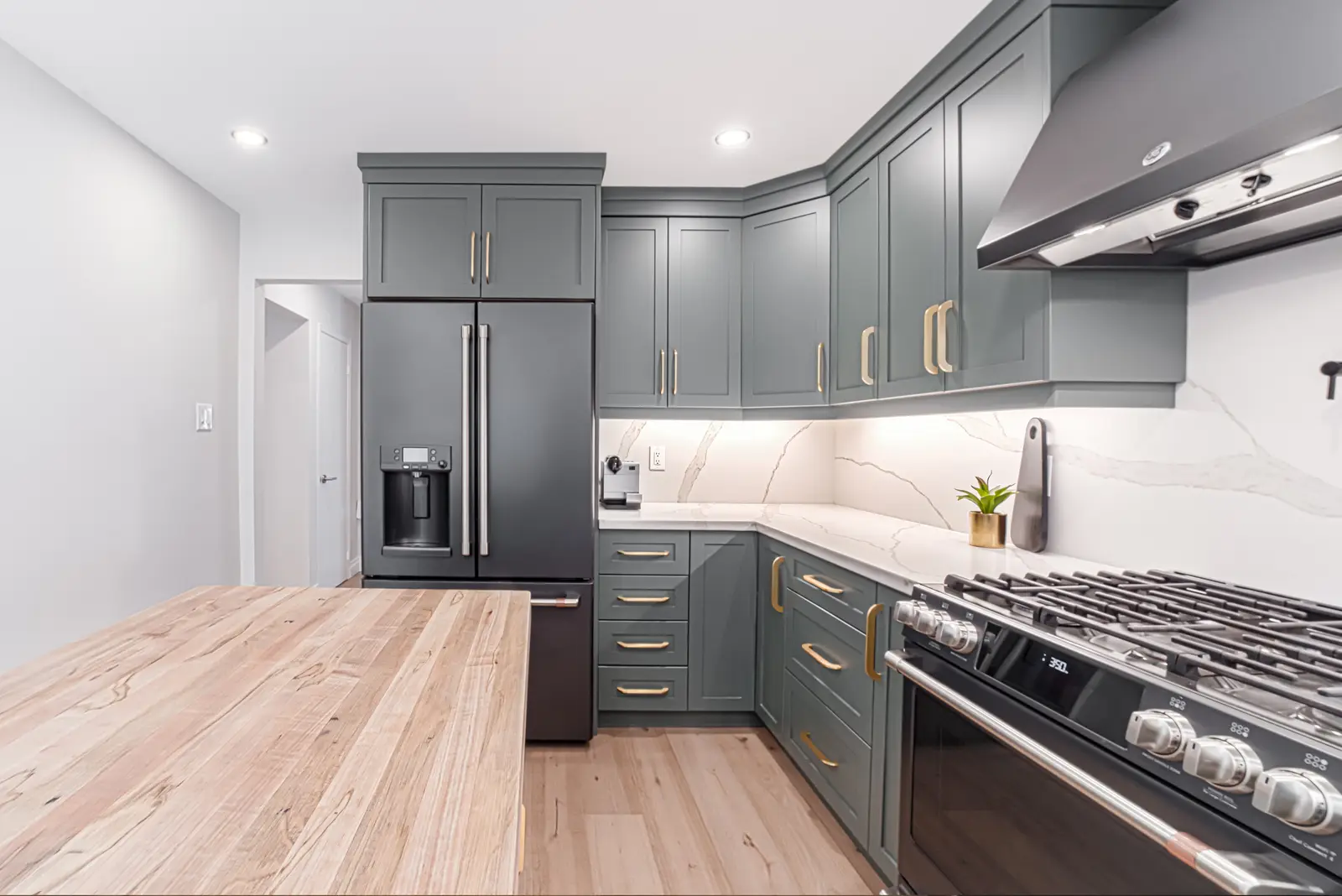 Interior of a Thornhill house renovation, with sage cabinetry, light wood floors, walnut, and brass fittings.