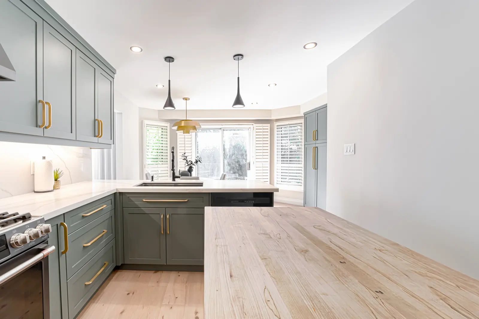 Interior of a Thornhill house renovation, with sage cabinetry, light wood floors, walnut, and brass fittings.