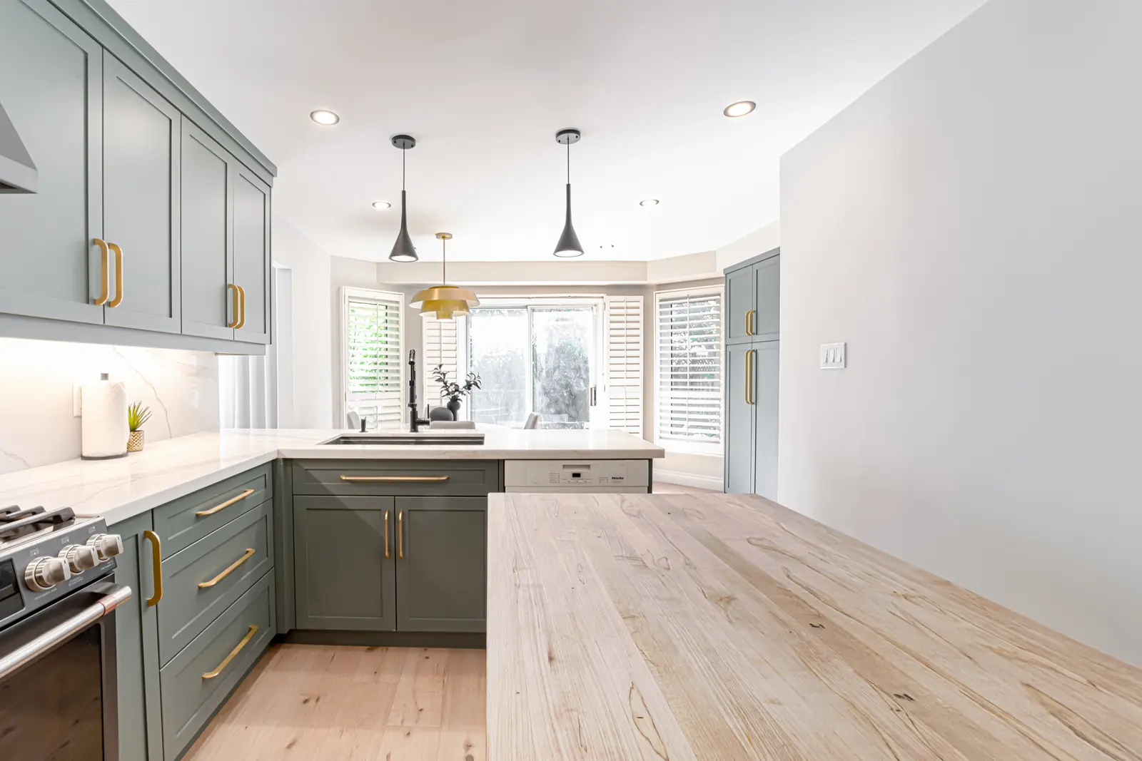 Interior of a Thornhill house renovation, with sage cabinetry, light wood floors, walnut, and brass fittings.