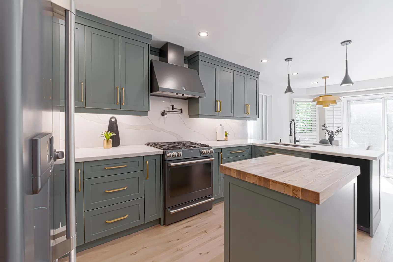 Interior of a Thornhill house renovation, with sage cabinetry, light wood floors, walnut, and brass fittings.