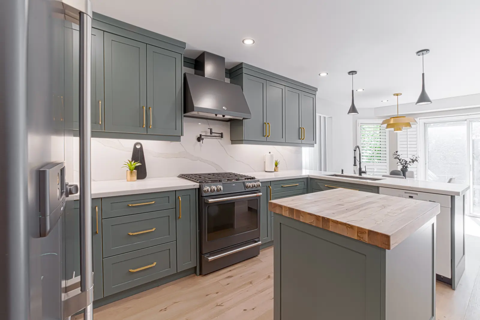 Interior of a Thornhill house renovation, with sage cabinetry, light wood floors, walnut, and brass fittings.