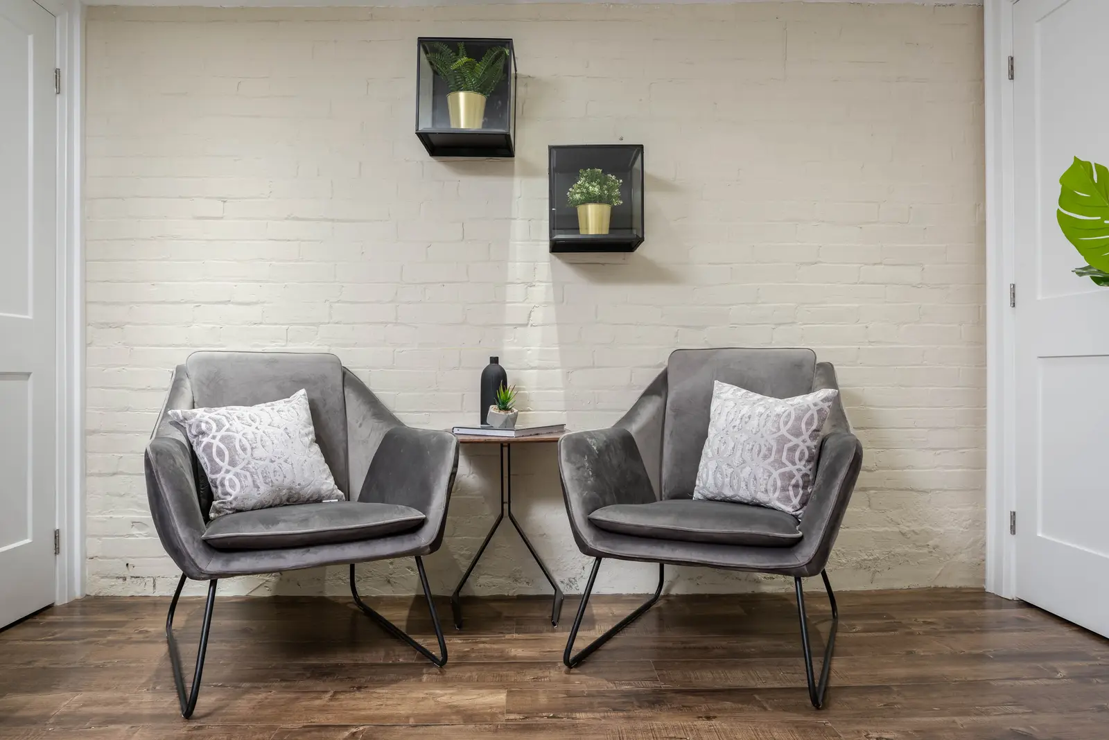 Interior of the house at 309 Manning Avenue in Toronto, with grey chairs, a painted brick wall, and dark wood floors.