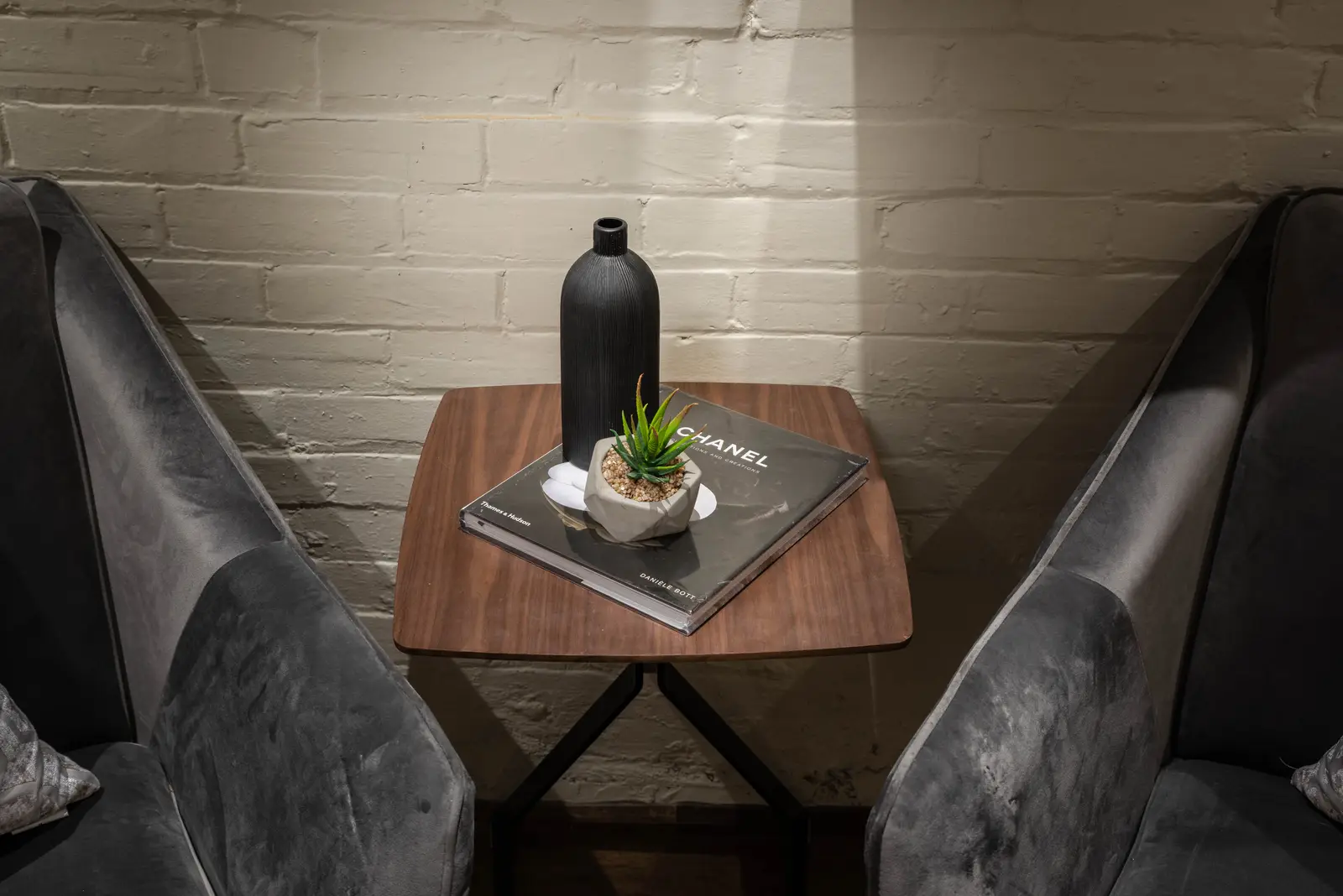 Interior of the house at 309 Manning Avenue in Toronto, with grey chairs, a painted brick wall, and dark wood floors.