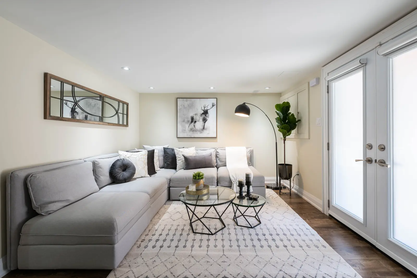 Interior of the house at 309 Manning Avenue in Toronto, with grey chairs, a painted brick wall, and dark wood floors.